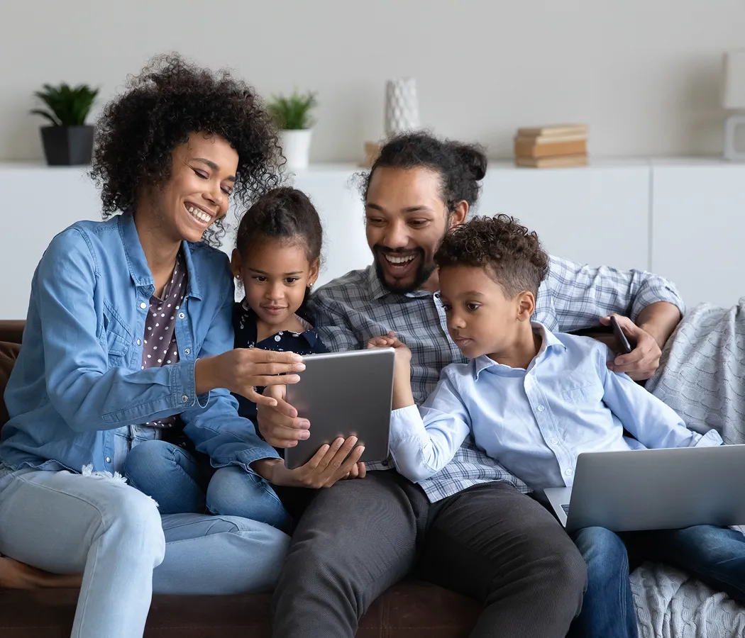 Family exploring learn-to-earn app for kids together on tablet.