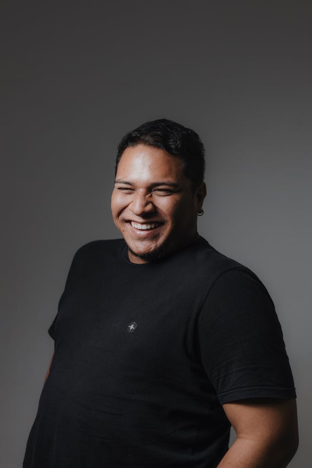 Image of a man wearing black clothing and laughing.