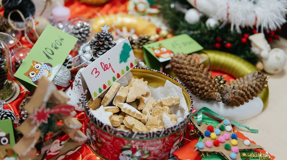 Az adventi vásár egyik asztalán láthatók a gyerekek által készített termékek: karácsonyi díszek és mézeskalács.