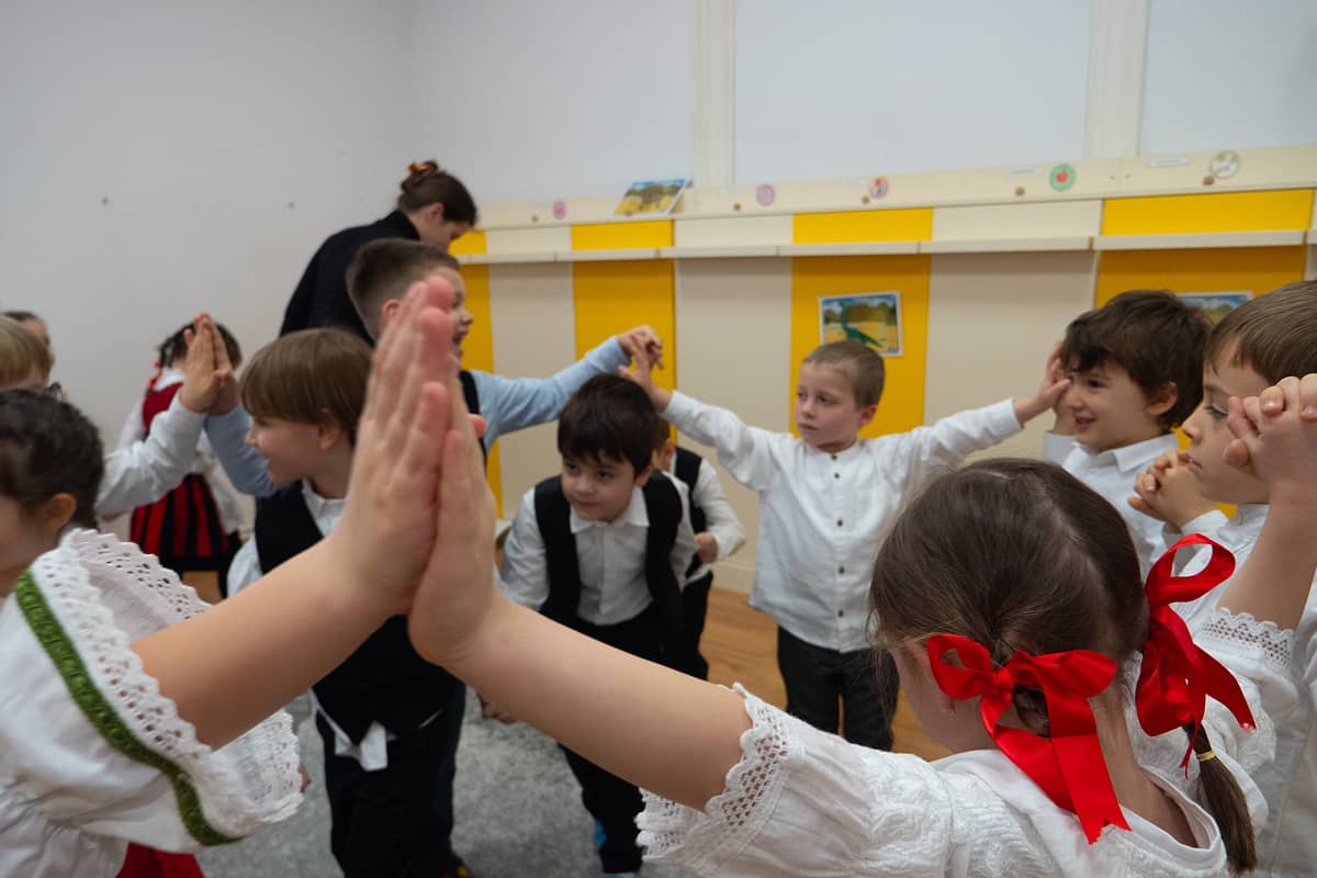 Copii de grădiniță joacă un joc de cerc, îmbrăcați în costume populare.