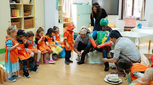 Szülők és gyermekek közösen készítenek télűző bábút a farsangi ünnepségen.