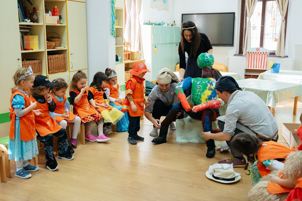 Părinții și copiii confecționează împreună o păpușă de alungare a iernii în cadrul sărbătorii de carnaval.