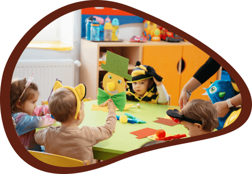 Bölcsődés gyermekek farsangi jelmezekben kézműves tevékenységen vesznek részt.