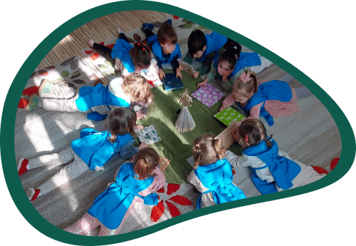 Óvodás gyermekek hason fekve nézegetik az ajándékba kapott könyveket.