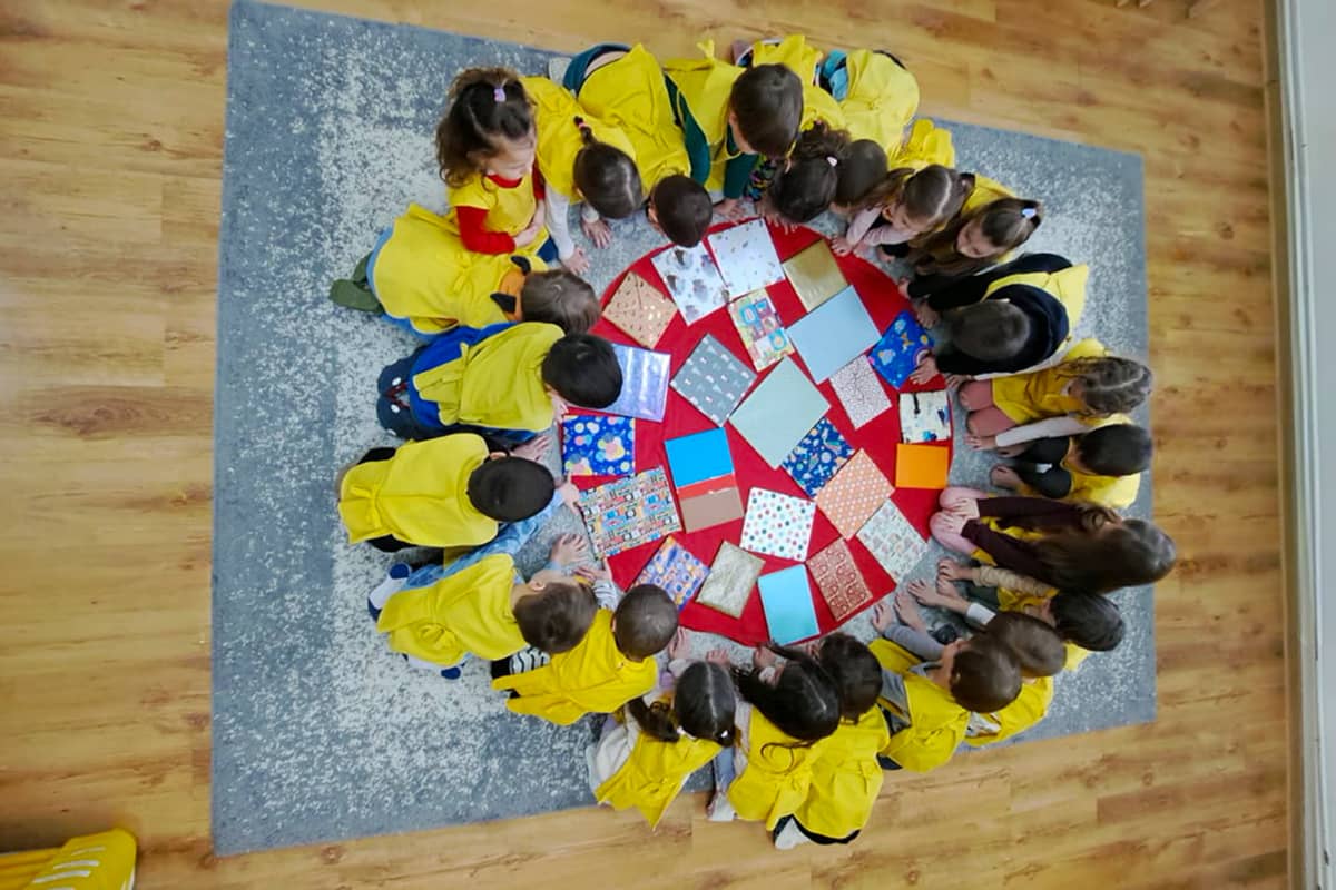 Gyermekek körben ülnek, középen a becsomagolt könyvekkel.