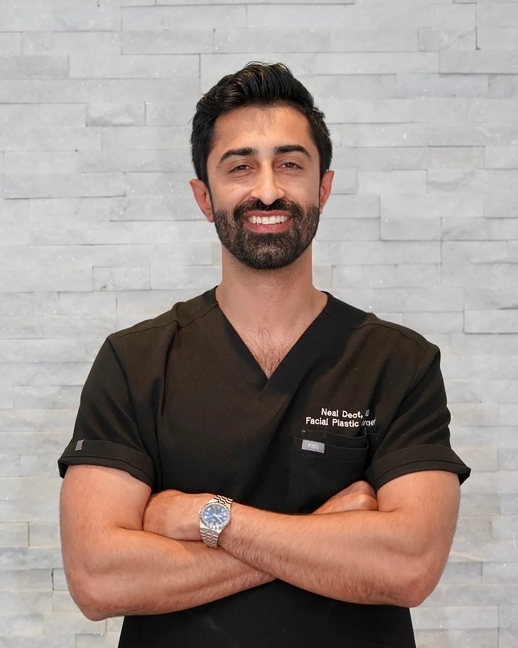 Dr. Neal Deot smiling in medical scrubs, facial plastic surgeon