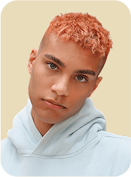 Portrait d’un homme aux cheveux courts cuivrés, portant un sweat bleu clair, regardant droit vers l’objectif.