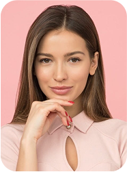 Portrait d’une femme souriante sur fond rose, portant une chemise rose pastel et la main posée sur son menton.