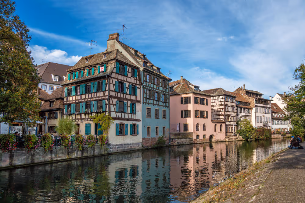 Bunte Fachwerkhäuser an einem Fluss an einem Sommertag die eine passende Lösung bei der Wohngebäudeversicherung brauchen