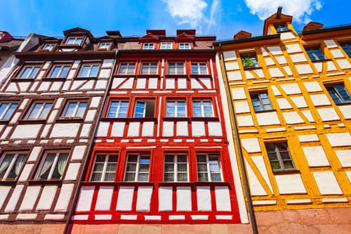 Farbig gefasste Fachwerkfassaden mit klarer Gliederung und denkmalgeschütztem Ensemblecharakter.