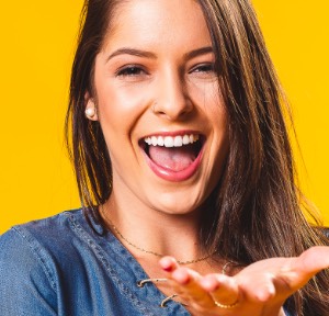 Blonde vrouw lachend voor een geel achtergrond