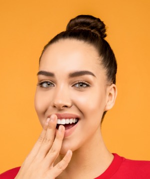 Vrouw met rode t-shirt voor een gele achtergrond met haar hand voor haar mond