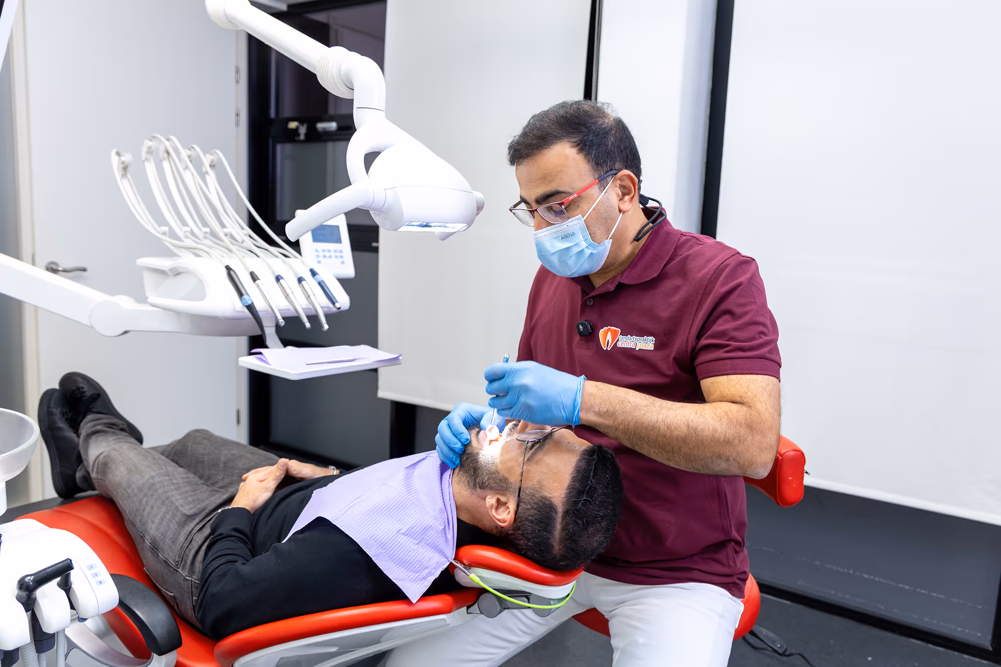 Mannelijke tandarts dat een mannelijke patiënt behandeld