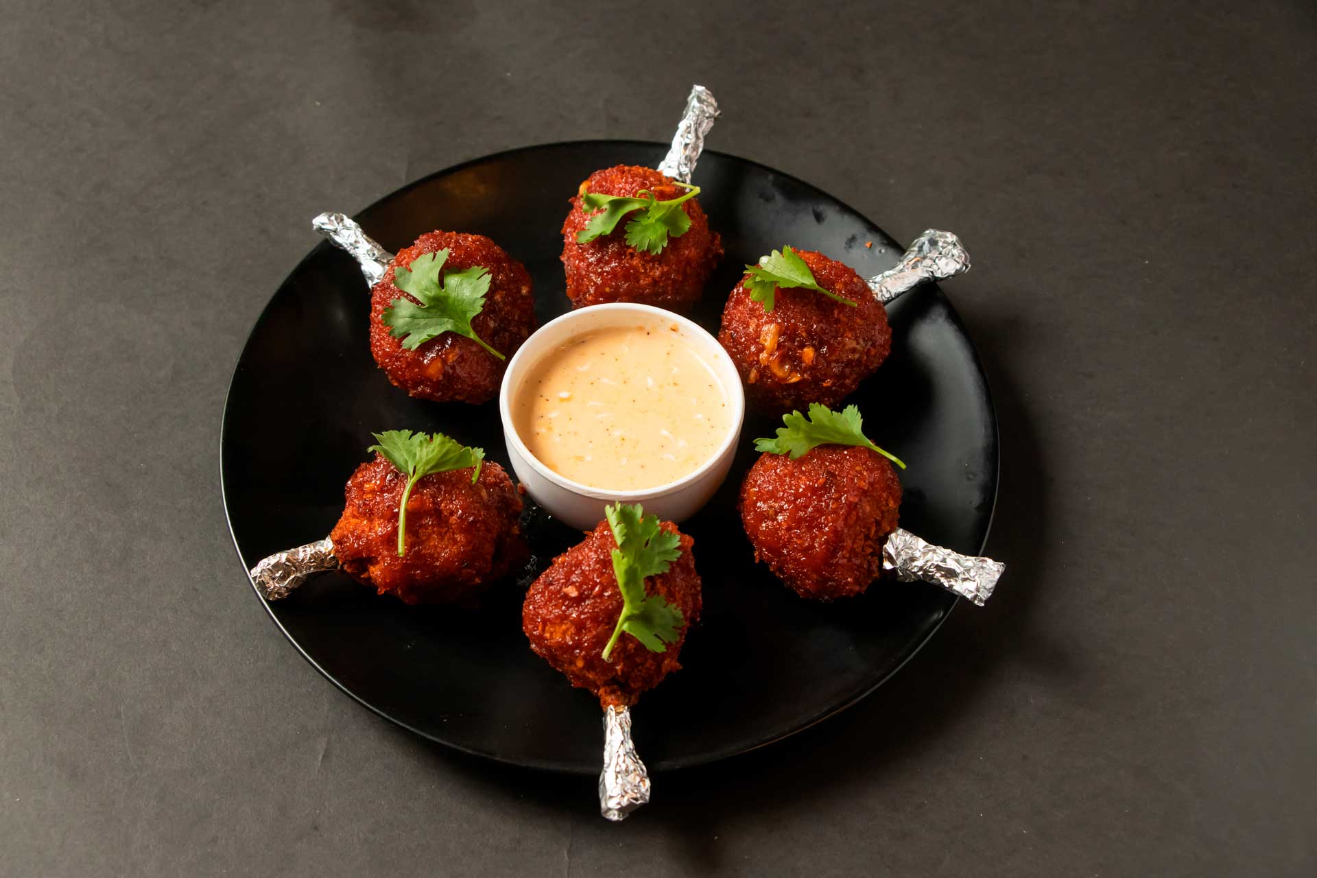 A dish featuring multiple chicken lollipops, presented appetizingly on a white plate