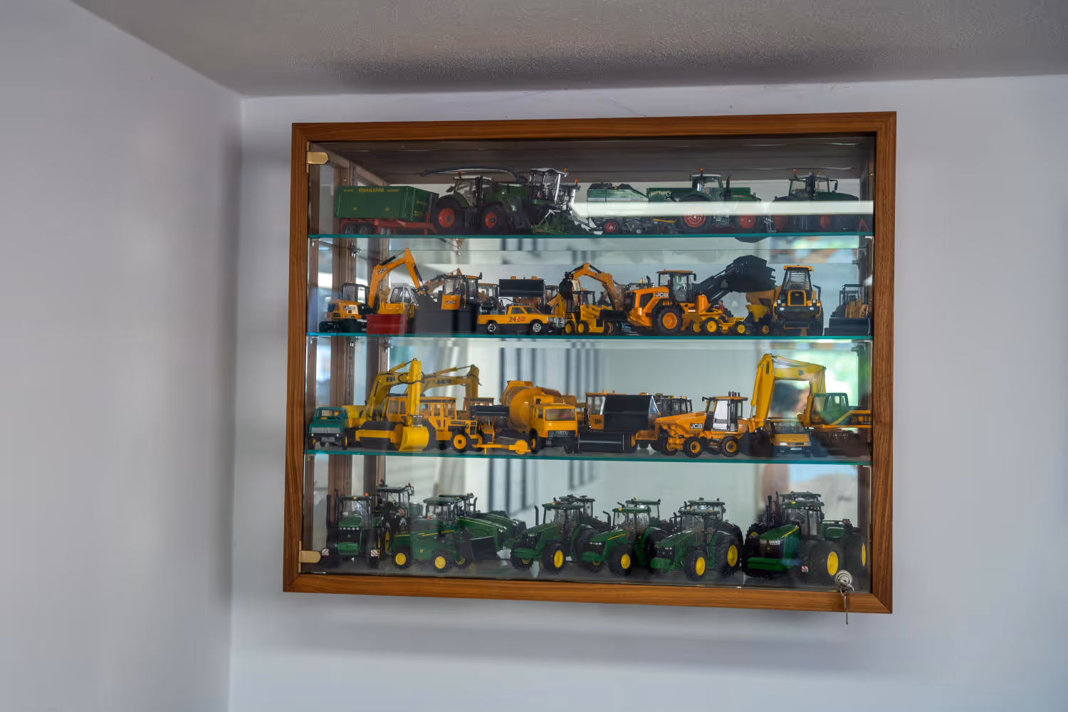 Vitrine mit detailgetreuen Modelltraktoren und Baumaschinen im Büro von Zeltsperger Immobilien.