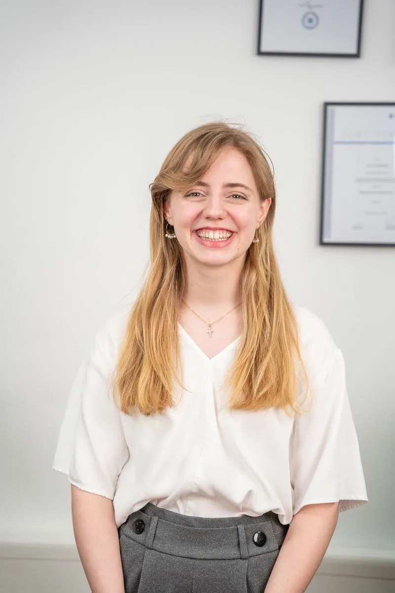 Maria Zeltsperger steht vor einer weißen Wand mit Bilderrahmen.