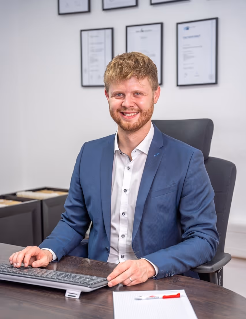 Rupert Zeltsperger trägt ein blaues Sakko und sitzt an einem braunen Tisch mit einer Tastatur.