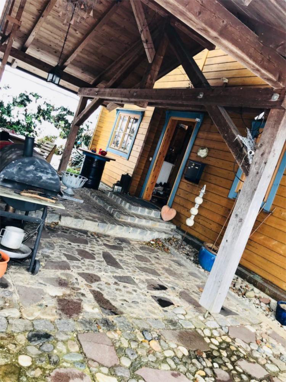 Überdachter Eingangsbereich mit Natursteinboden und Holzfassade, Einfamilienhaus in Bad Endorf, Zeltsperger Immobilien.
