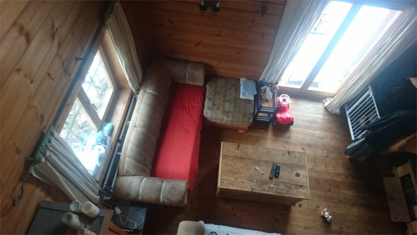 Wohnzimmer mit Holzwänden, Couch und großen Fenstern, Einfamilienhaus in Bad Endorf, Zeltsperger Immobilien.
