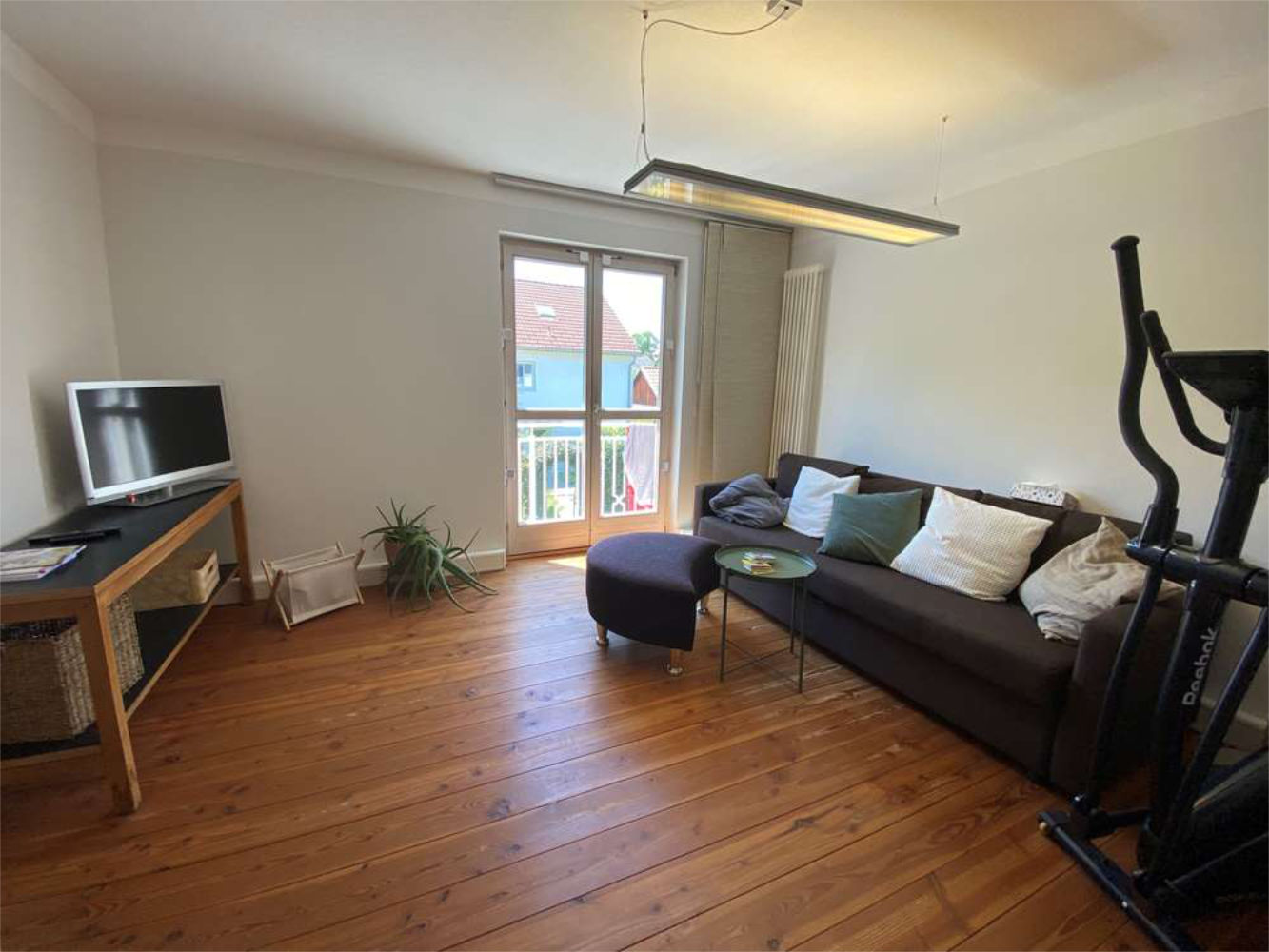 Gemütliches Wohnzimmer mit Holzboden und Zugang zum Balkon, Zeltsperger Immobilien.