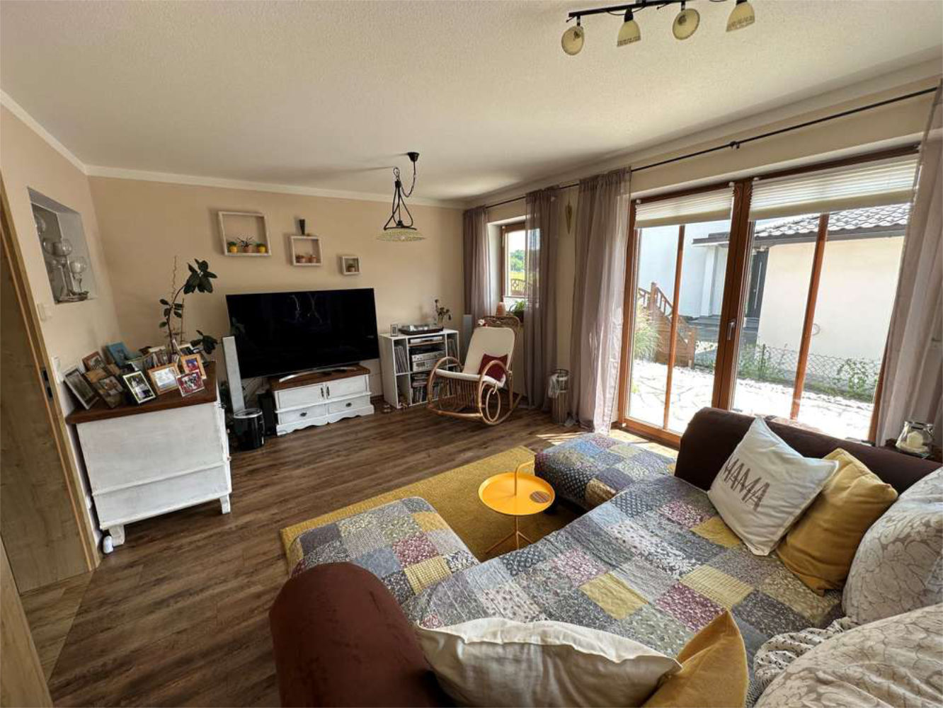Gemütliches Wohnzimmer mit großer Couch und Zugang zur Terrasse, Zeltsperger Immobilienobjekt.