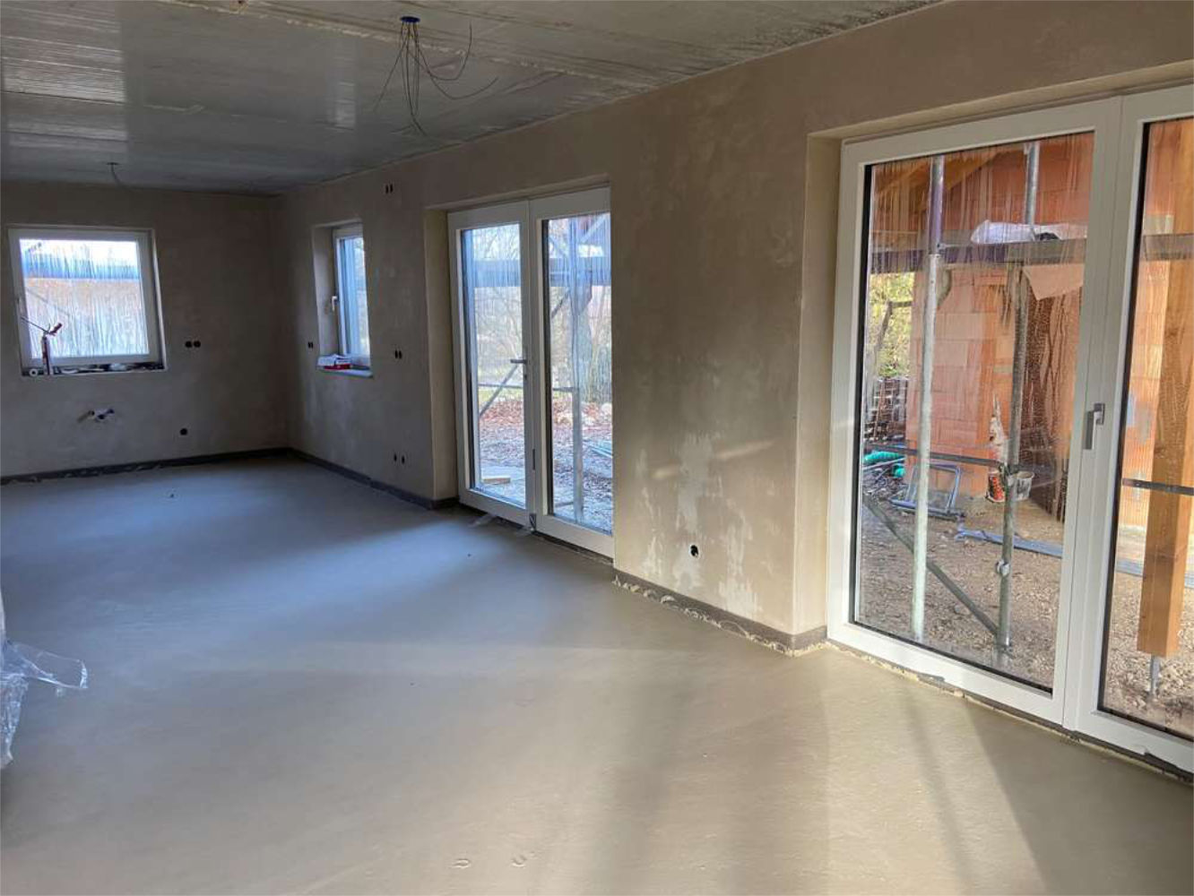 Neubau im Rohbauzustand mit großen Fenstern und Terrassenzugang, Zeltsperger Immobilien.