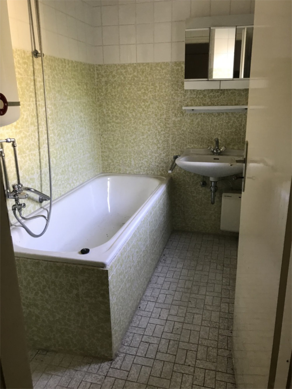 Badezimmer mit grünen Fliesen und Badewanne in älterer Immobilie, Zeltsperger Immobilienbestand.