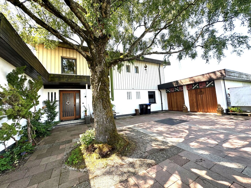Einfamilienhaus mit weißer Fassade, Flachdach, überdachter Terrasse, großem Carport, gepflegtem Garten mit altem Baumbestand und sonniger Lage – familienfreundliches Eigenheim in ruhiger Siedlung.