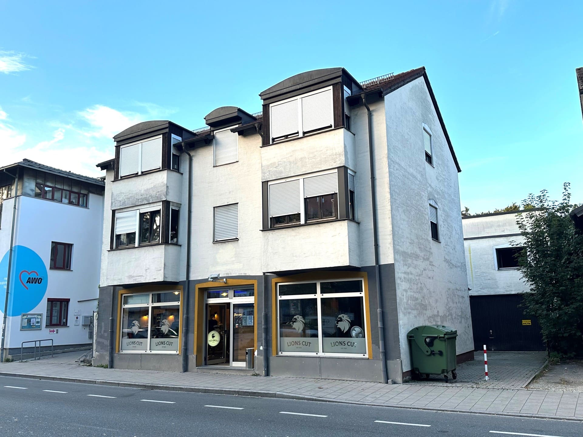 Modernes Reihenhaus mit weißer Fassade, großem Garagenhof, bodentiefen Fenstern, Balkonen und sonniger Lage in familienfreundlicher Siedlung – energieeffizientes Eigenheim mit Bergblick.