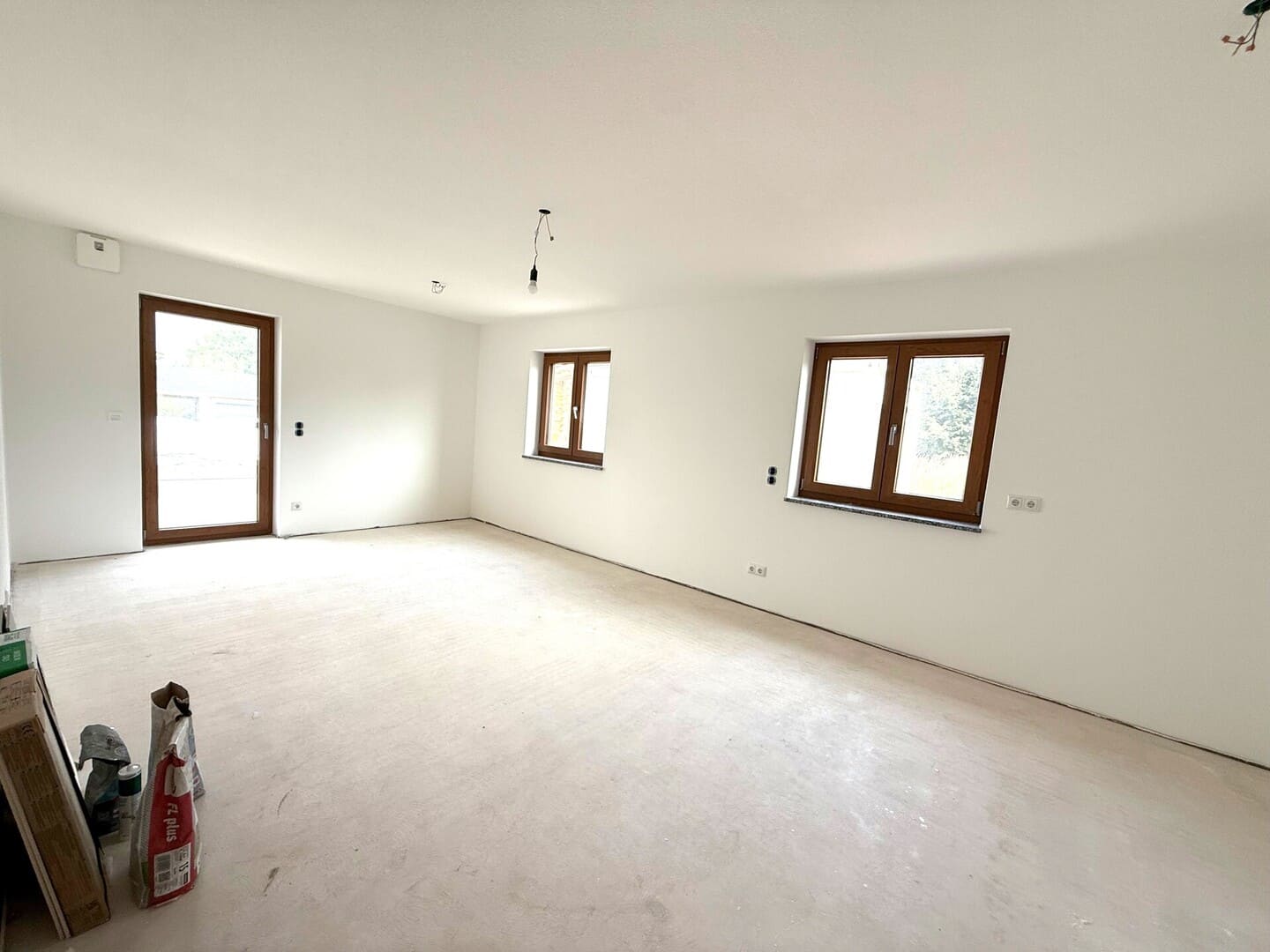 Helles Wohnzimmer mit Fenstern und offener Küche – großzügige 2-Zimmer-Wohnung im Erstbezug