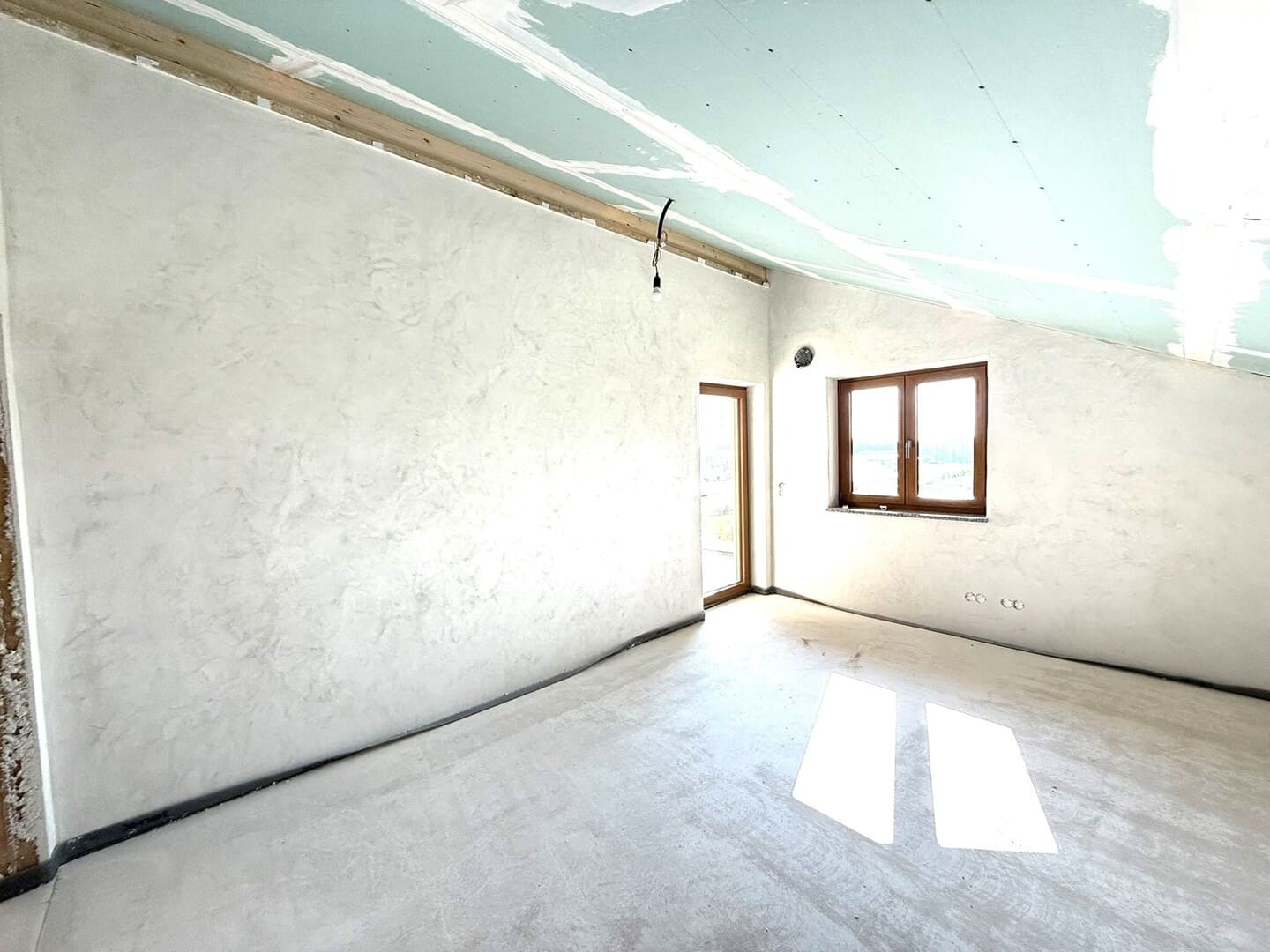 Schlafzimmer im Neubau mit Dachschräge und großem Fenster – helle Räume mit angenehmem Raumgefühl.