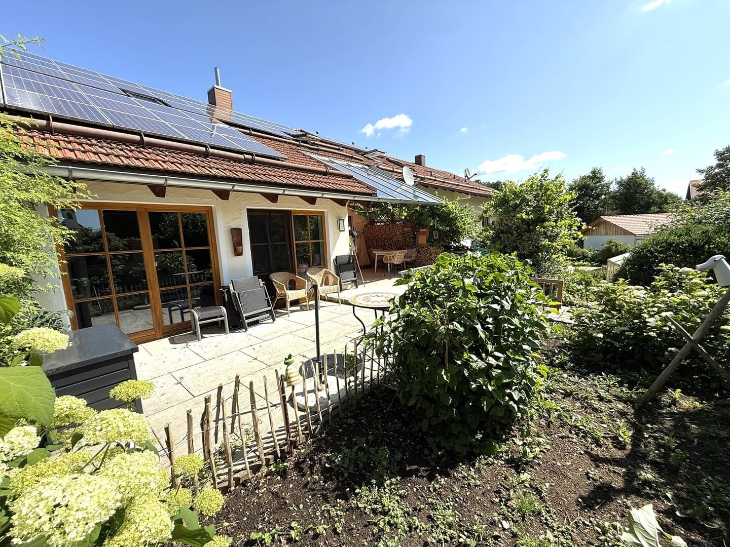 Terrasse mit Steinbelag und liebevoll angelegtem Garten – sonnige Südwestlage in Obing.