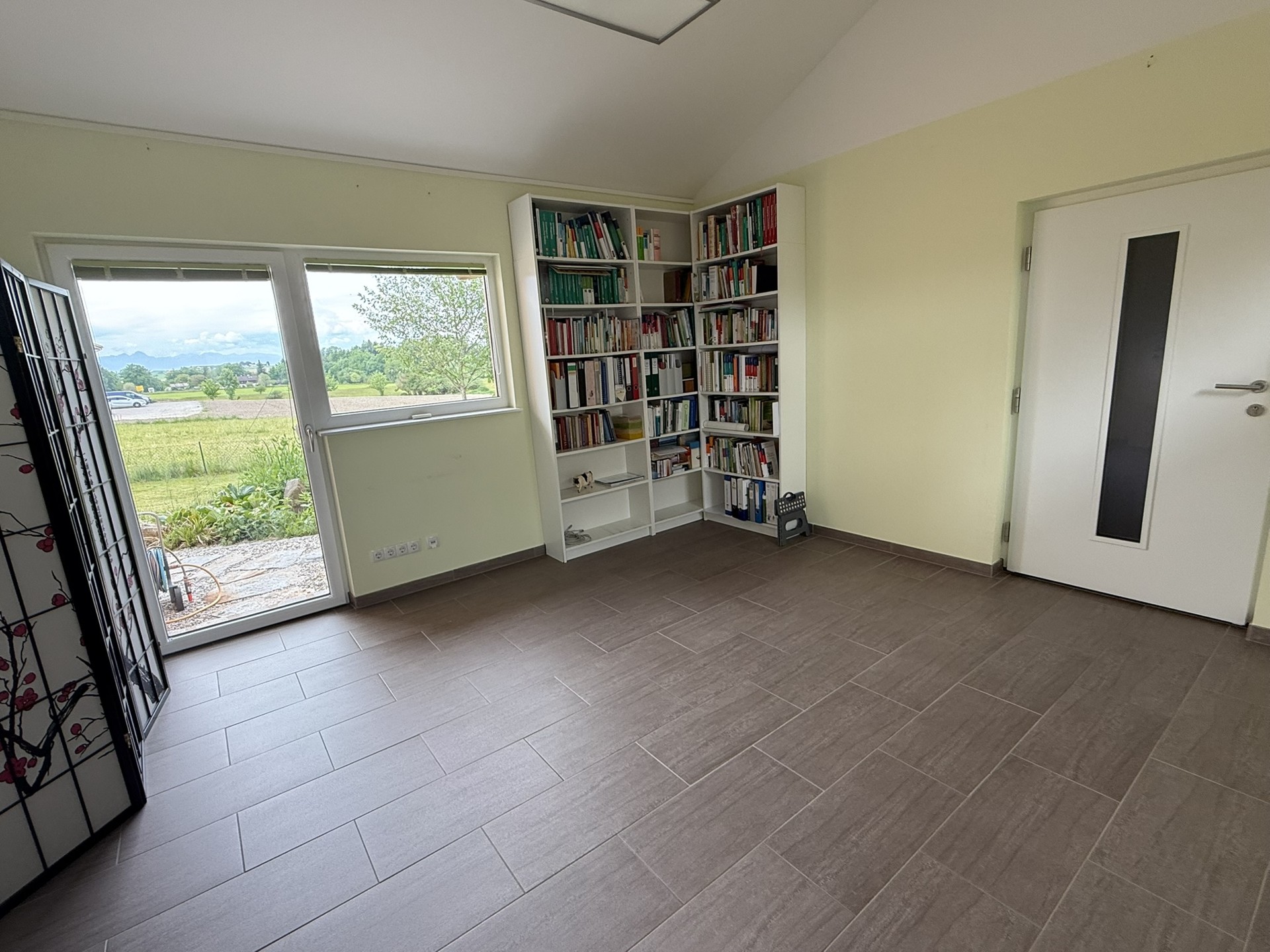 Helles Zimmer mit großem Fenster und hellem Boden.