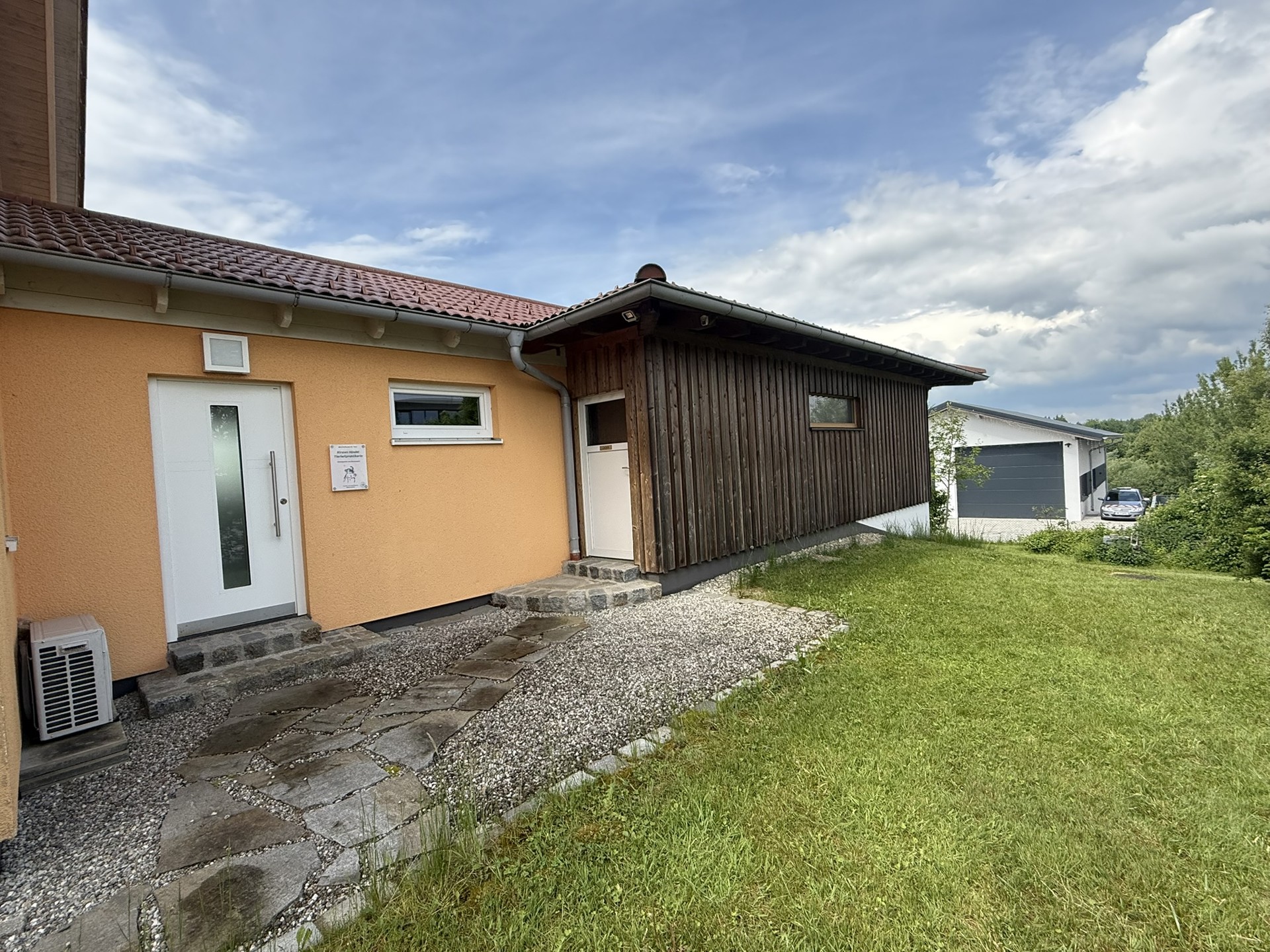 Außenansicht eines Einfamilienhauses mit Carport, Wiese und Hof.