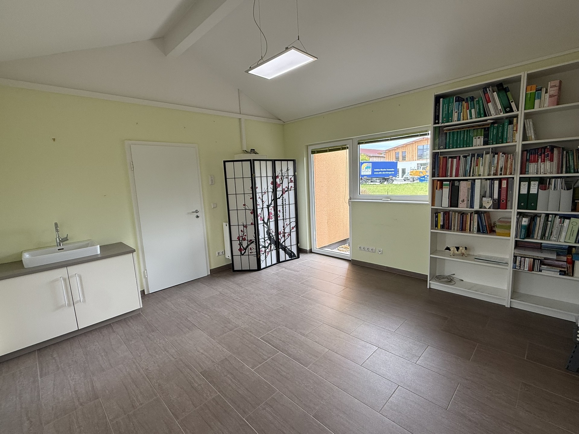 Offene Wohnküche mit grünen Wänden und Blick auf Terrasse.