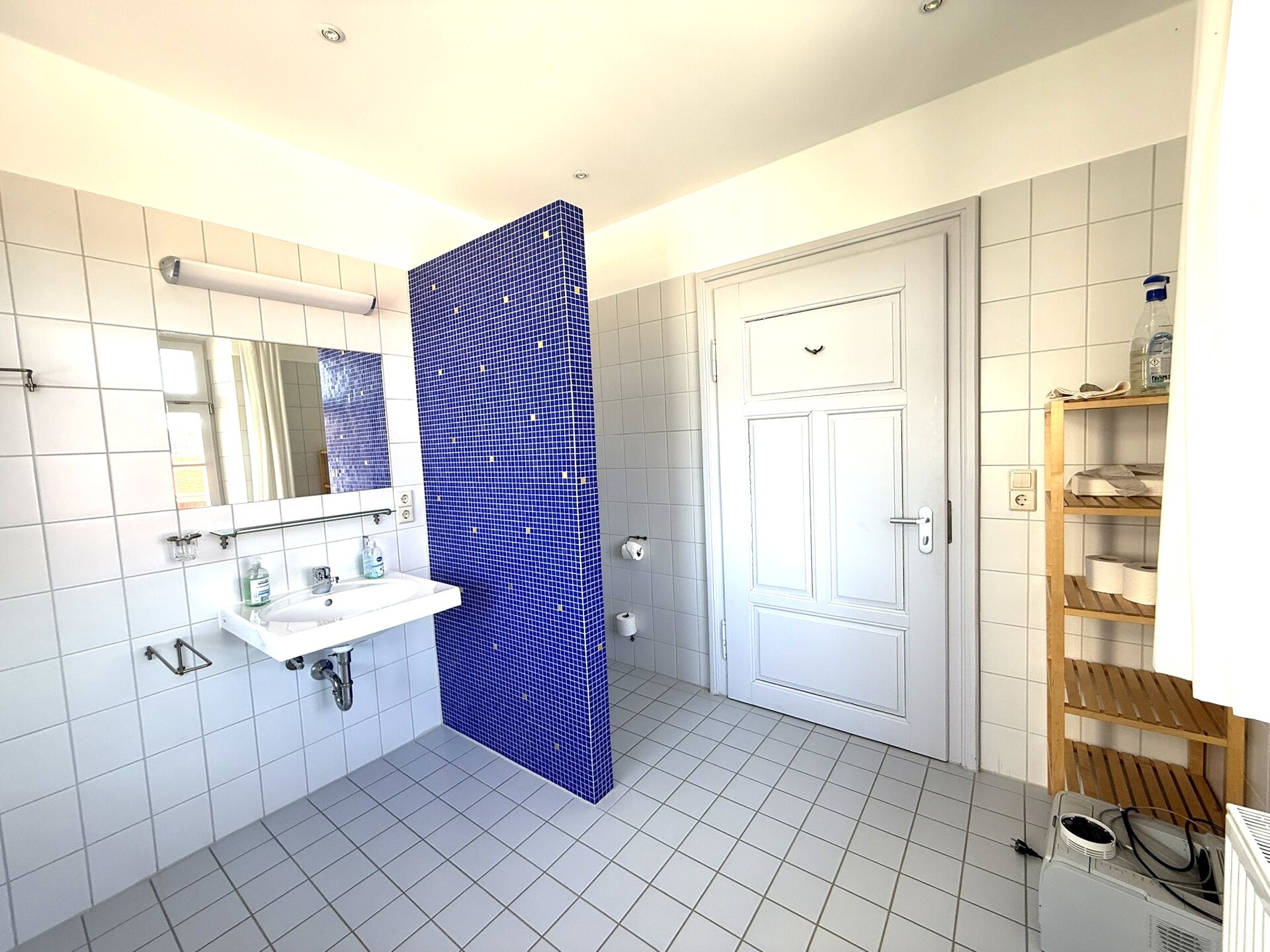 Badezimmer mit zwei Waschbecken, großer Spiegelwand und blau gefliester Dusche.