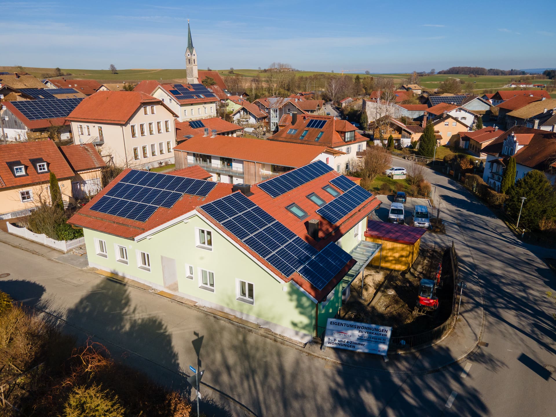 Moderner Essbereich mit Holztisch und blauen Stühlen, offener Küche mit Tresen und großen Fenstern zum Garten.