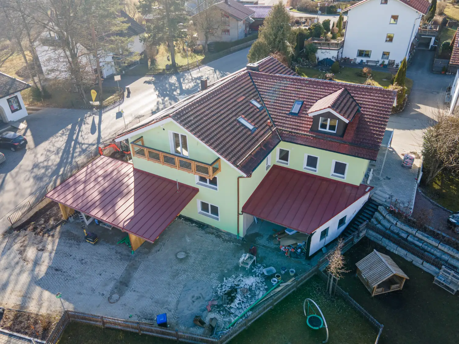 Luftaufnahme eines sanierten Mehrfamilienhauses mit neuem Dach, Balkon und moderner Fassade in ruhiger Wohnlage in Tengling
