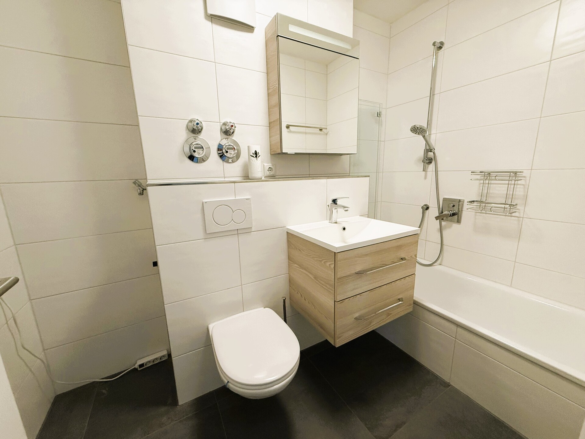Modernisiertes Badezimmer mit Badewanne, Waschtisch und WC in der 2-Zimmer-Wohnung