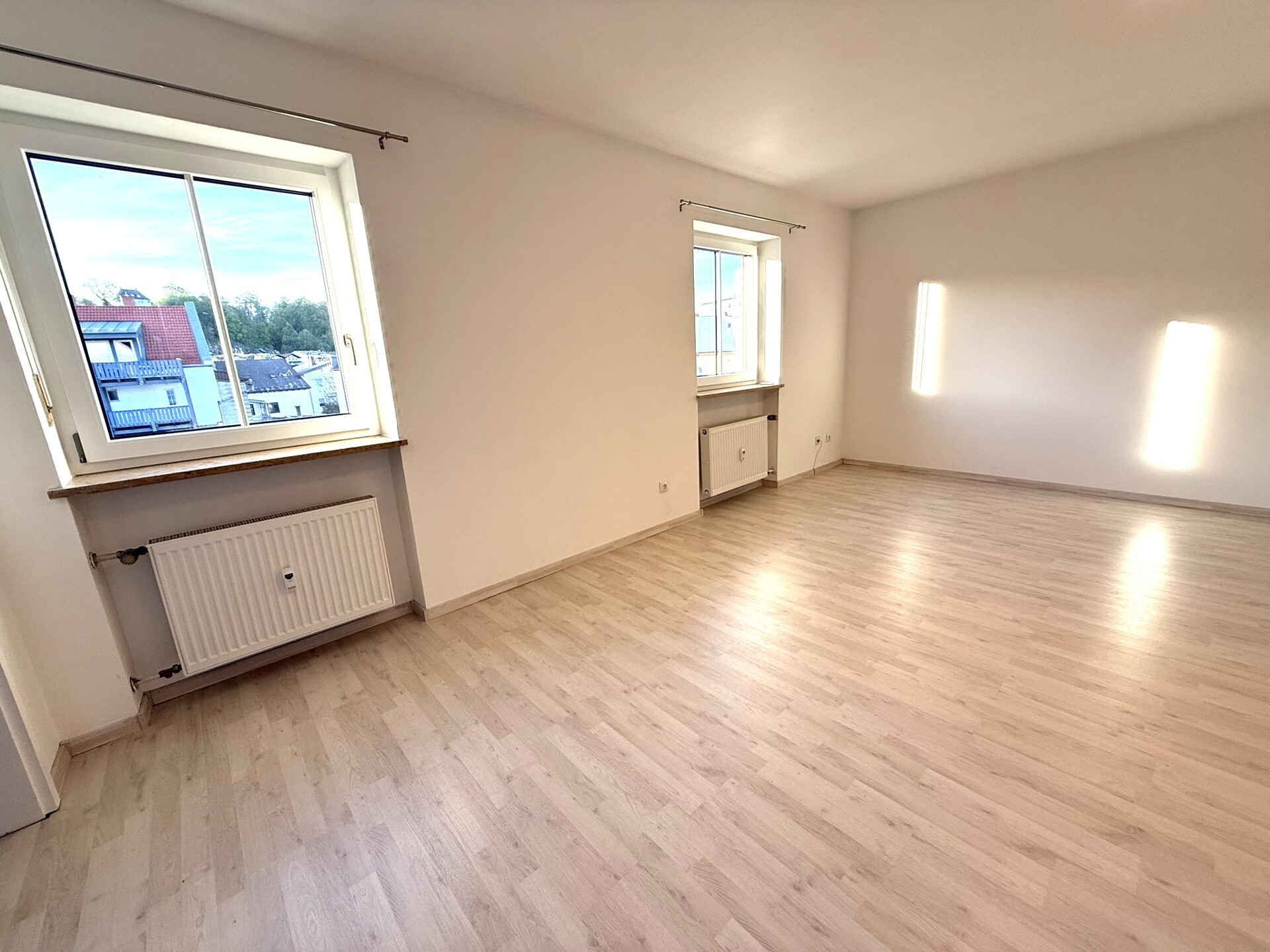 Helles Wohnzimmer der modernisierten 2-Zimmer-Wohnung in Trostberg mit großem Fenster und Parkettboden