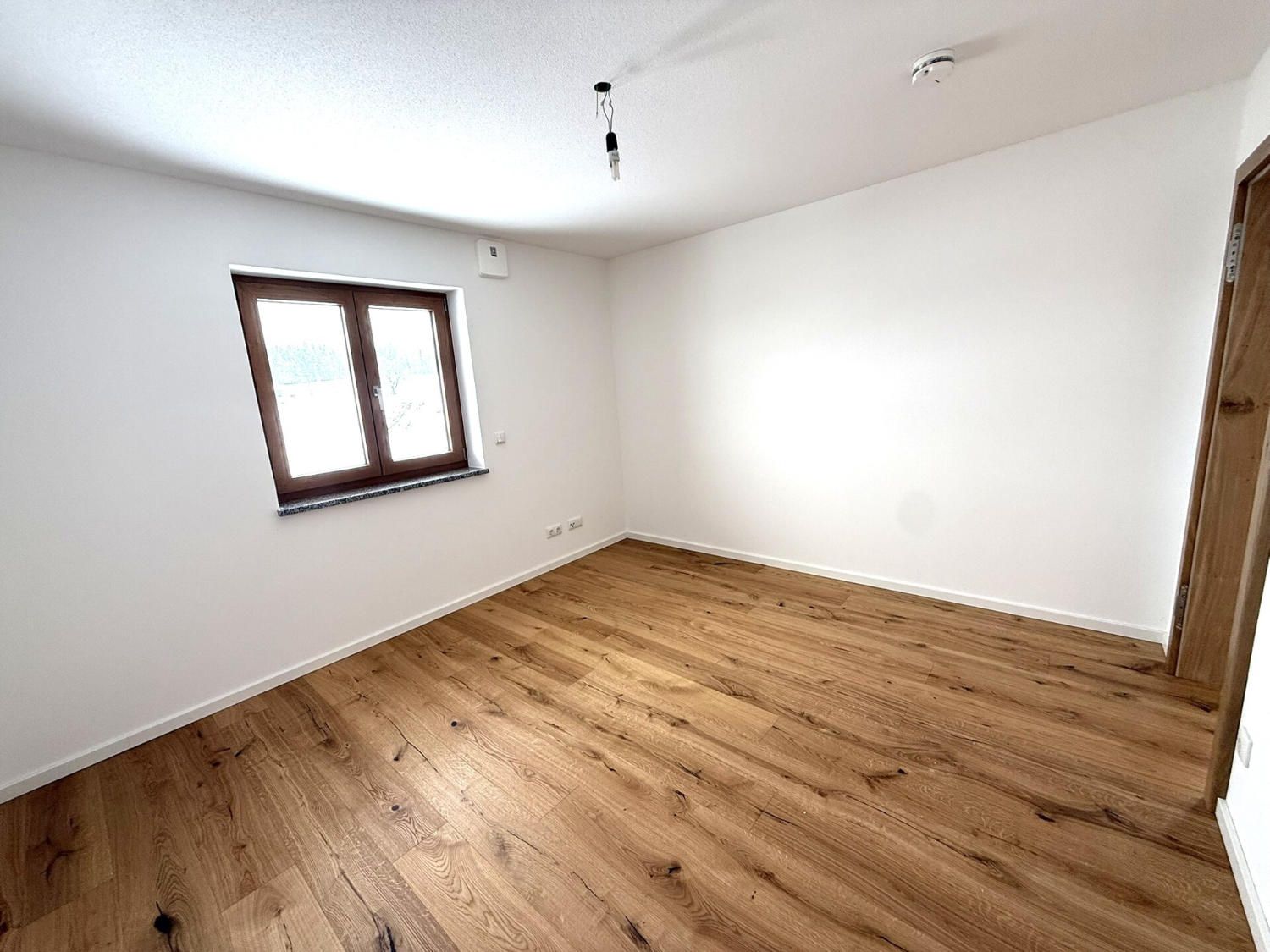 Moderner Essbereich mit Holztisch und blauen Stühlen, offener Küche mit Tresen und großen Fenstern zum Garten.