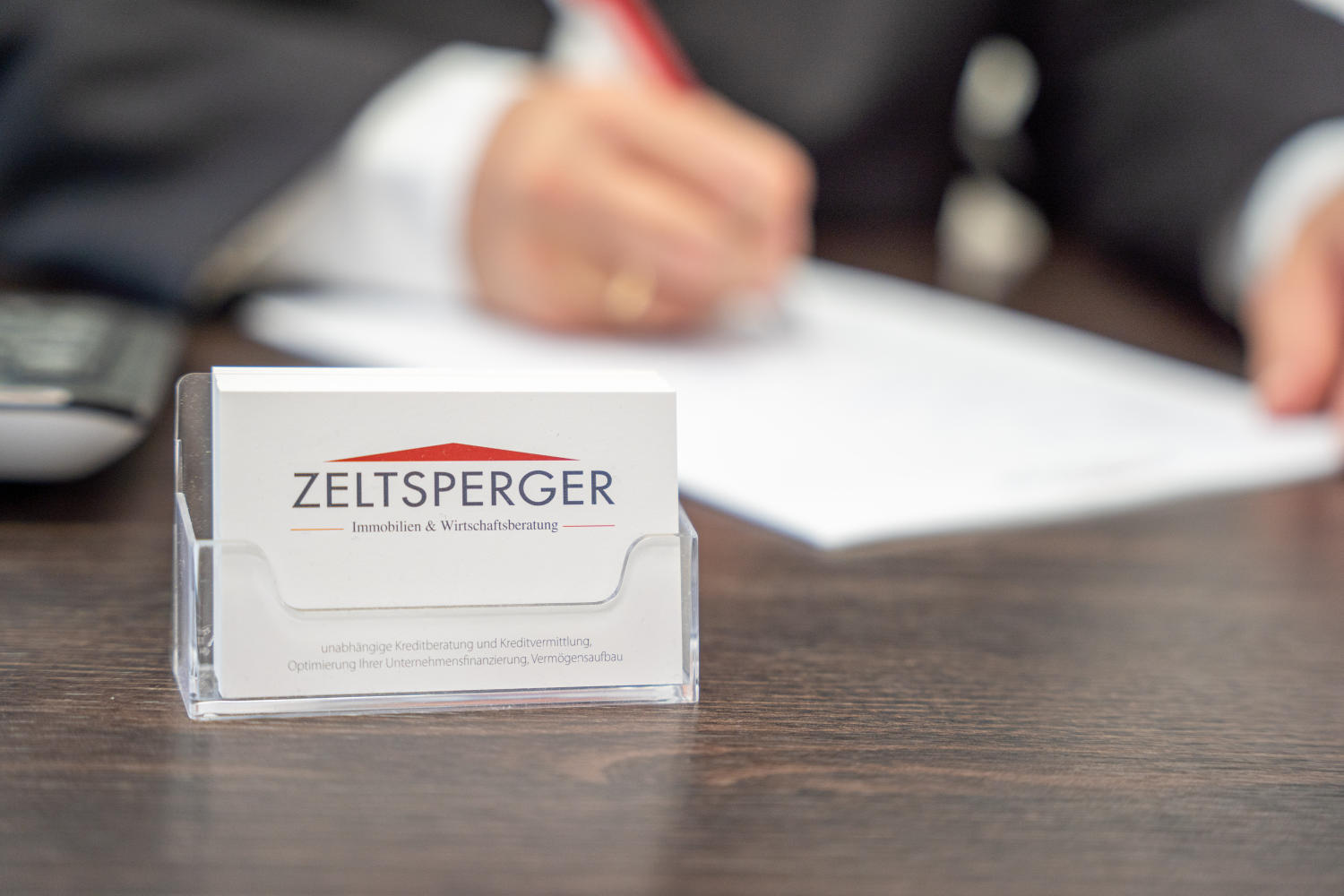 Zeltsperger VIsitenkarte auf braunem Tisch mit Unterlagen