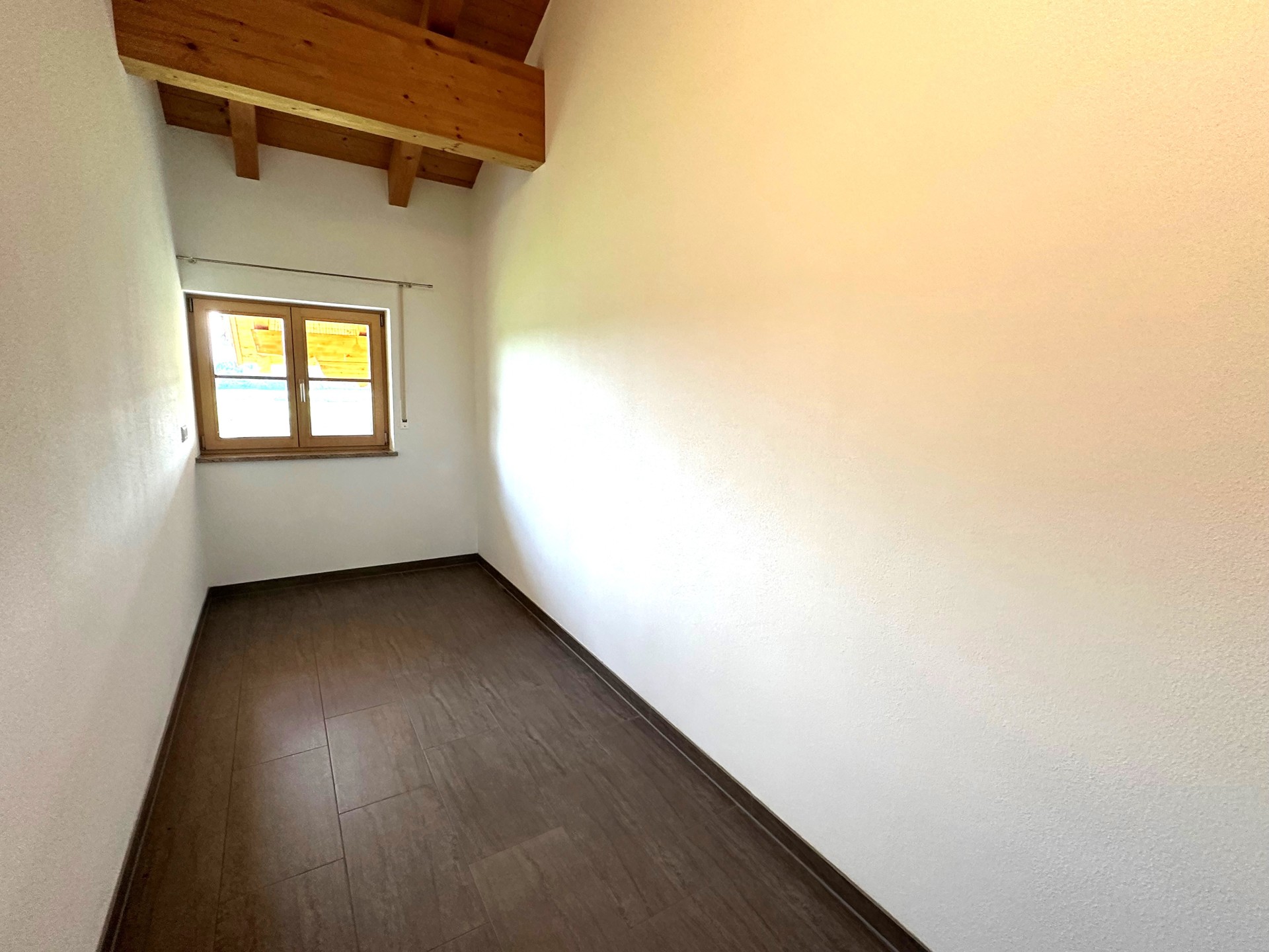 Heller Raum mit dunklem Holzboden und zwei Fenstern.
