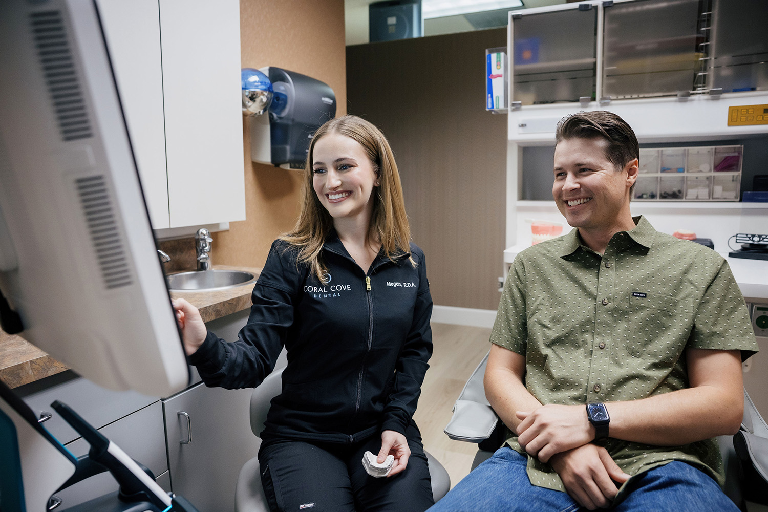 Female dental professional showing a male patient a screen in a dental office.
