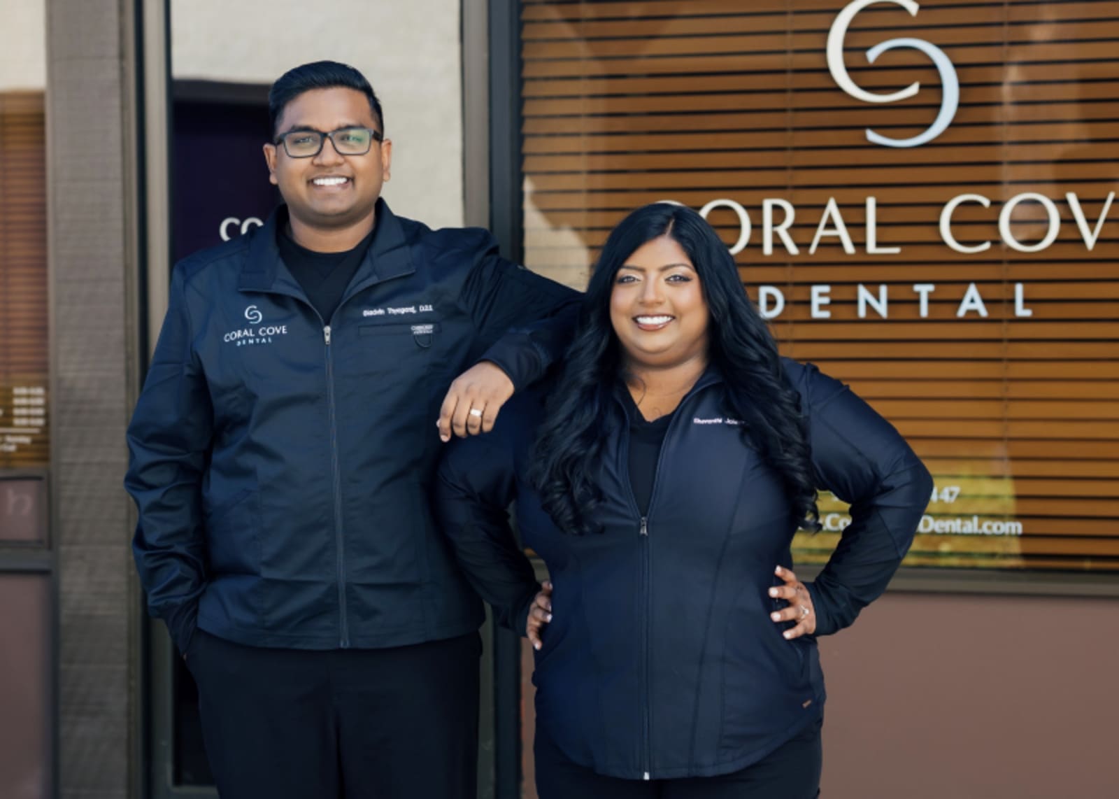 Male dentist and female patient posing together at Coral Cove Dental office entrance