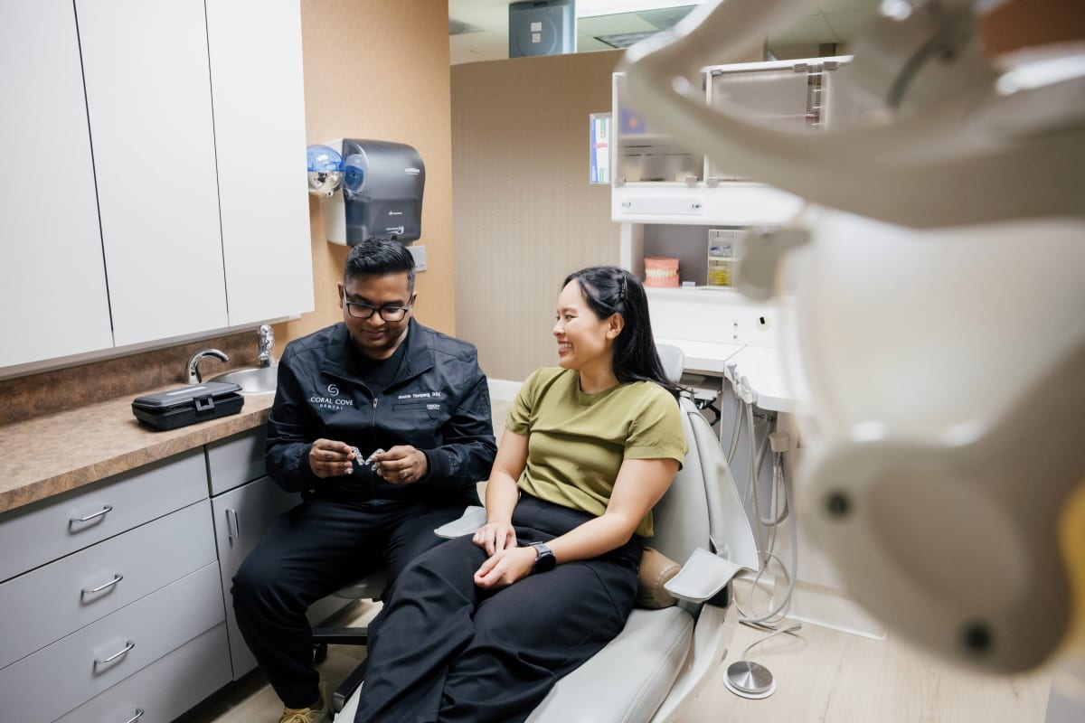 Female dentist in black jacket examining patient in dental treatment chair