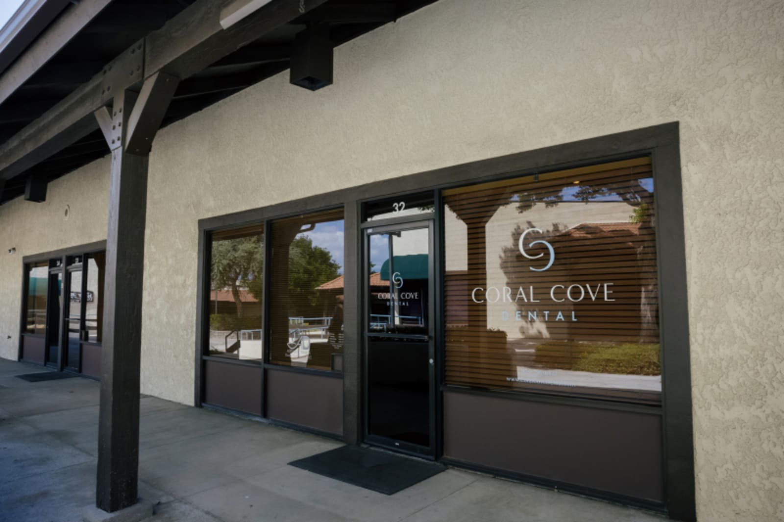 Coral Cove Dental storefront exterior at dusk with illuminated signage