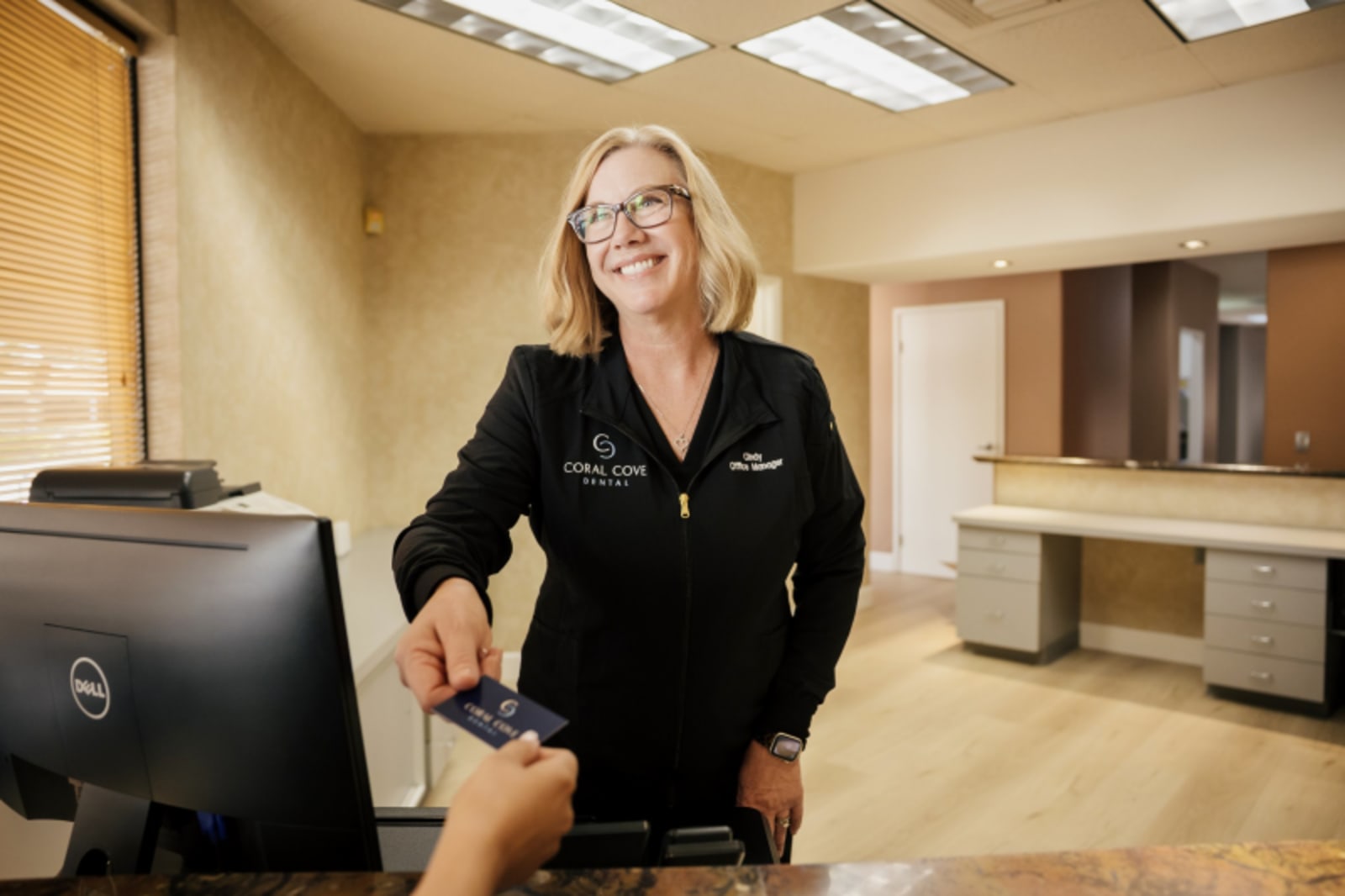 Dentist in dark jacket standing in modern dental office treatment area