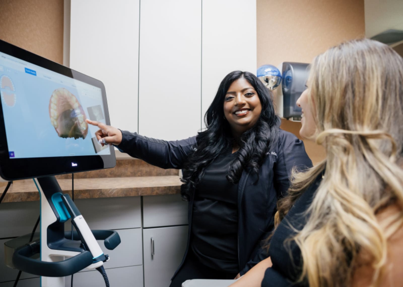 Dental team member consulting with patient at computer workstation in office