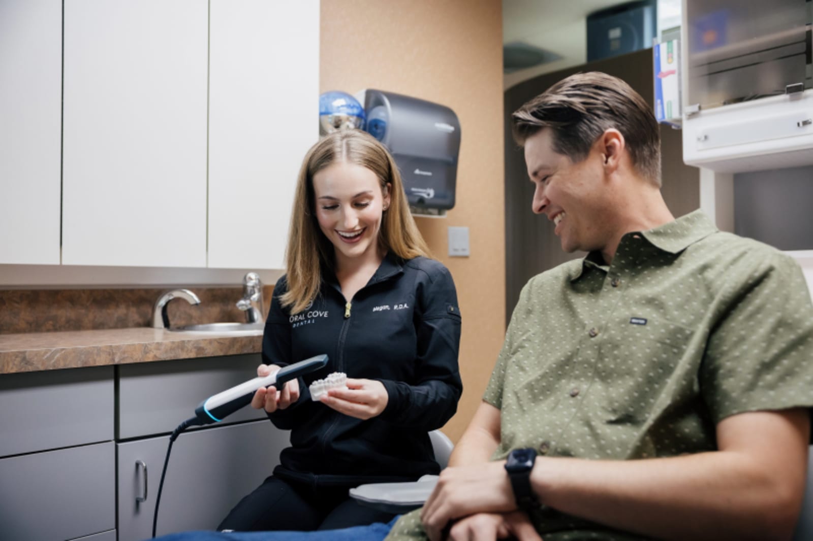 Female dentist showing dental treatment information to patient during consultation